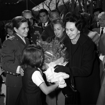 Eva Sámano recibe flores de una niña al llegar a la inauguración de la escuela militar que lleva su nombre
