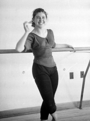 Bailarina recargada en la barra de ejercicios en una academia de Ballet, retrato