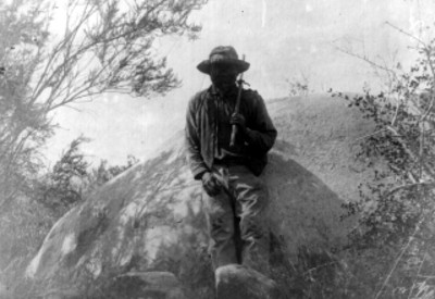 Hombre tarahumara recargado en una gran piedra, retrato