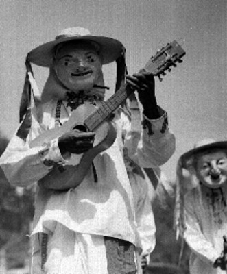 Purepecha con mascara y traje regional tocando guitarra durante la fiesta de un poblado