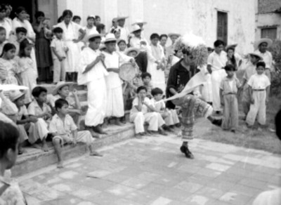 Danzante Totonaca bailando, acompañado por músicos en el atrio de la parroquia de Papantla
