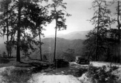 Autos estacionados sobre un camino con vista hacia las montañas