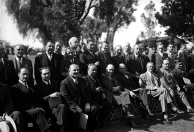 José Manuel Puig Casauranc acompañado de otras personalidades en un jardín durante un acto, retrato de grupo