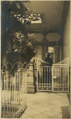 Mujer detrás de la reja de una casa habitación, retrato