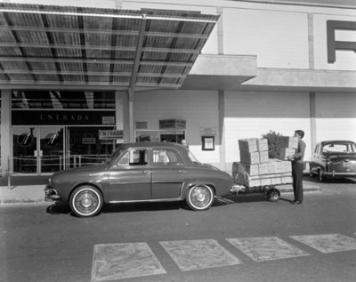 Automóvil con mercancia estacionado frente a la entrada de una atienda comercial