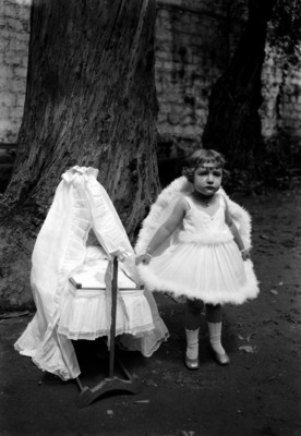 Niña vestida de ángel en el jardín de una escuela