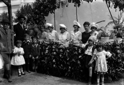 Mujeres acompañadas de niños y hombres en un puesto de una kermesse, retrato de grupo