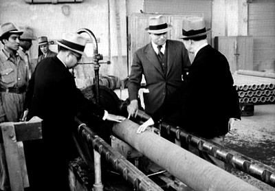 Banqueros observando maquinaría manufactura de tubos de concreto en fábrica Eureka