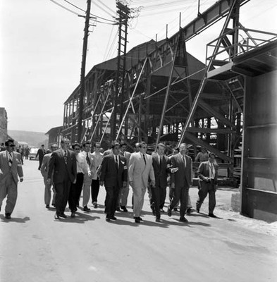 Adolfo López Mateos con otras personas, recorriendo las instalaciones de una planta industrial, durante su gira electoral por Monclova
