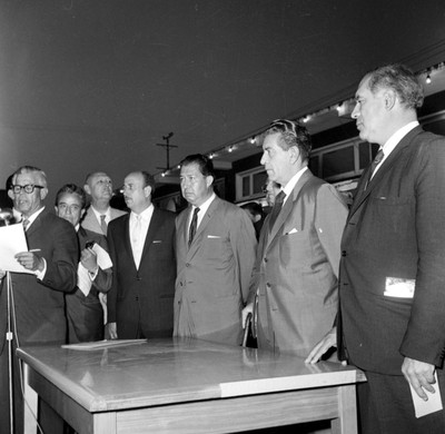 Adolfo López Mateos con otras personas ante el discurso de un hombre durante una ceremonia en Ensenada