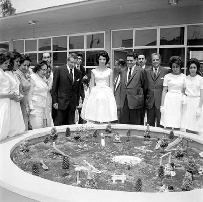 Adolfo López Mateos y comitiva observando una maquete exhibida en una escuela