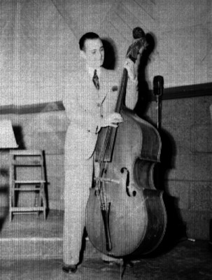 Miembro de la Sinfónica Nacional tocando un contrabajo en un estudio de radio durante un programa en la XELA