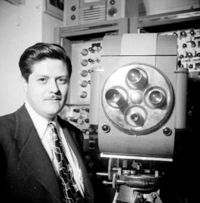 Hombre junto a una cámara en una cabina de radiodifusión