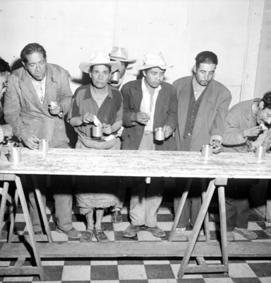 Ancianos toman sus alimentos de pie ante una mesa