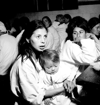 Mujer y niños toman sus alimentos en un albergue