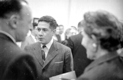 Mujer y hombres conversan durante una exposición de pintura