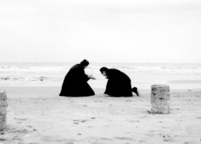 Monjas orando en la orilla del mar