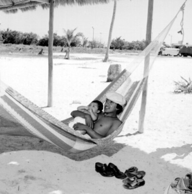 Hombre con niño en brazos sobre una amaca