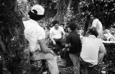 Grupo de hombres sentados a la sombra de unos árboles