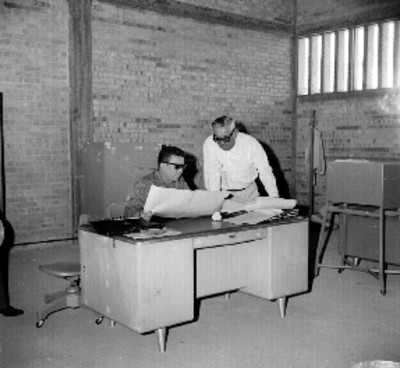 Roberto Amorós y comitiva ante la explicación de un hombre, en el interior de un almacén de depósito