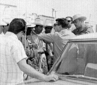 Roberto Amorós junto a un automóvil, atendiendo a campesinos