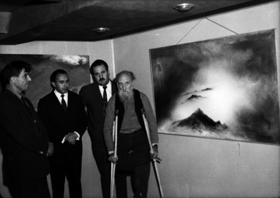 Gerardo Murillo acompañado por varios hombres, posando junto a una pintura realizada por él