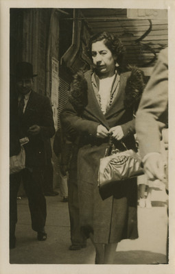 Mujer camina por una calle, viste un abrigo, tarjeta postal