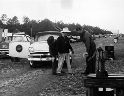 Inmigrante es revisado por policías en un campamento