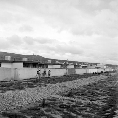 Hombres caminan en una calle de unidad habitacional