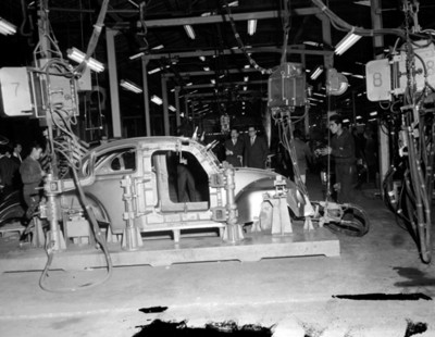Hombres observan ensamblaje de automóvil en planta automotriz Volkswagen