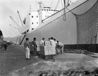 Trabajadores descargan mercancias de carros-plataforma en un embarcadero