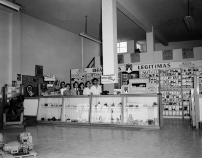 Empleados tras mostrador en tienda de refacciones automotrices, retrato de grupo