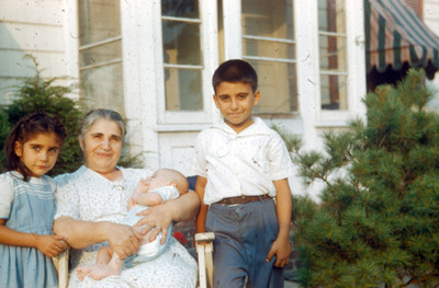 Niños junto a una mujer con bebe en brazos, retrato de grupo