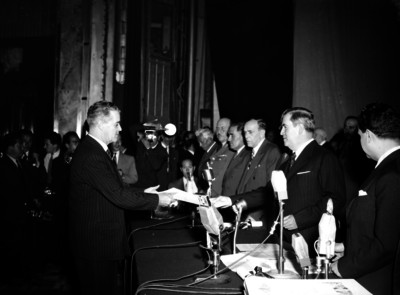 Manuel Ávila Camacho entregando reconocimiento a un hombre durante la ceremonia del 2° aniversario de alfabetización