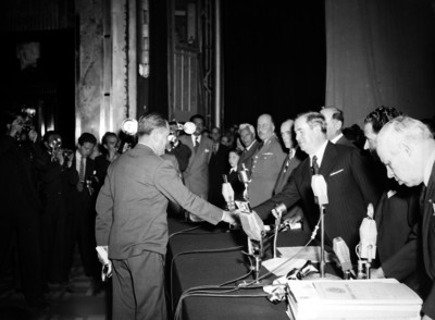 Manuel Ávila Camacho estrecha la mano de un hombre durante la ceremonia del 2° aniversario de alfabetización