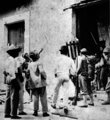 Hombres observan el exterior de una casa atacada por norteamericanos