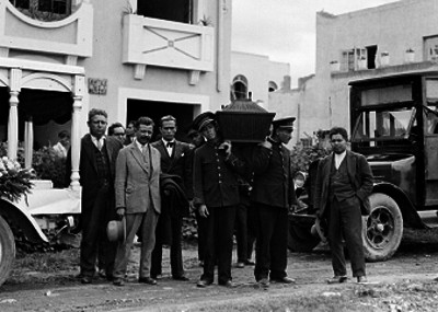 Empleados de la agencia funeraria Alcázar conducen féretro a una carroza fúnebre