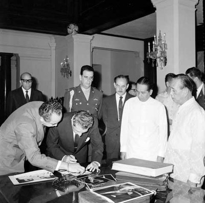 Adolfo López Mateos acompañado de funcionarios públicos firmando un documento en la bilblioteca de Filipinas