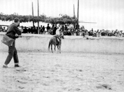 Hombre vestido de charro monta a caballo sobre rodeo