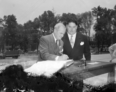 Hombre firma en un libro durante ceremonia pública