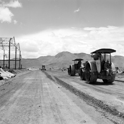Maquinas aplanadoras en carreteras junto a armazón de nave industrial