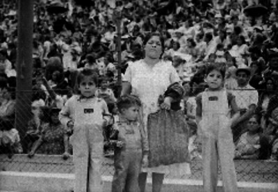 Mujer y tres niños parados frente a una multitud. posiblemente durante un sorteo