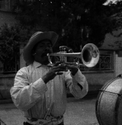Hombre con sombrero tocando la trompeta en la calle