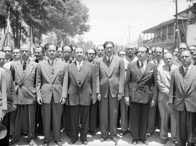 Miguel Alemán Valdés, acompañado por miembros de su comitiva y funcionarios públicos, en la calle, durante su gira por Michoacán, retrato de grupo