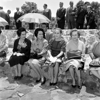 Eva Sámano de López Mateos con otras mujeres sentadas en una banca de piedra durante acro público en el Edo. de México