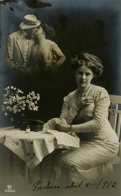 Mujer sentada frente a una mesa, al fondo una pareja besándose, tarjeta postal