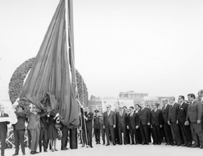 El presidente de la República Gustavo Díaz Ordaz acompañado de representantes del poder legislativo y judicial y de miembros de su gabinete izando la bandera nacional en el asta de la plaza Constitución