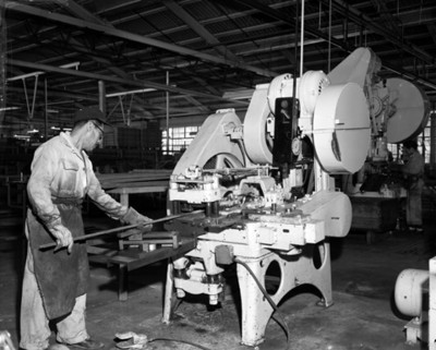 Trabajador coloca un metal dentro de una maquina industrial