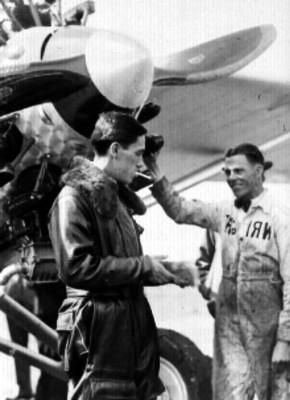 Emilio Carranza fumando un cigarro junto a mecánico y avión