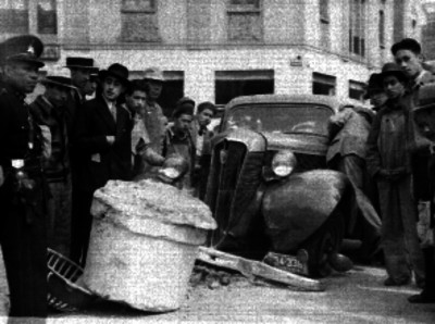 Policia y espectadores junto a un automóvil impactado contra un poste